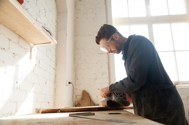 Free photo joiner polishes wooden board in workshop