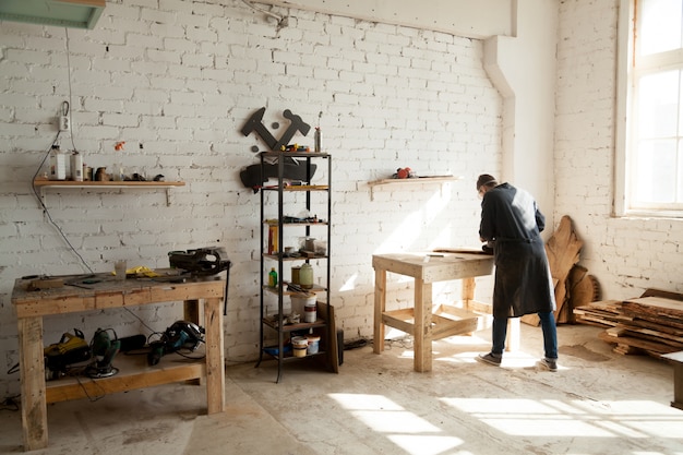 Joiner working at workbench in small carpentry