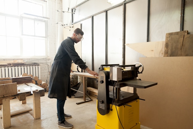 Jointer in protective workwear processing wood on stationary power tool