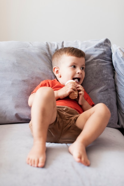 ソファーでアイスクリームを食べる陽気な少年