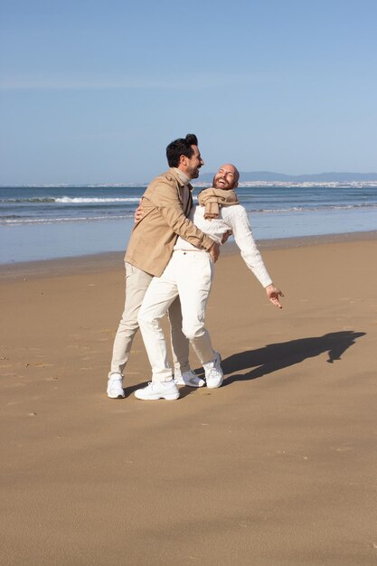 Jolly gay couple dancing on beach