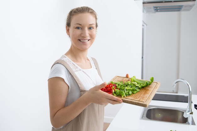 Jolly young woman showing cut fresh bell pepper