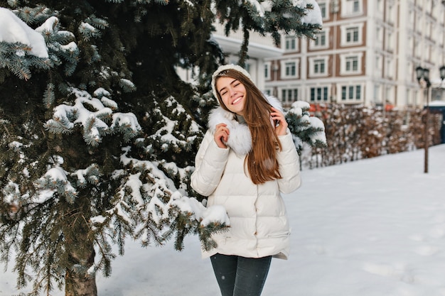 雪の空間でいっぱいの金のなる木に暖かい冬の服を着て笑っている素晴らしい美しい女の子の喜び、幸せ。