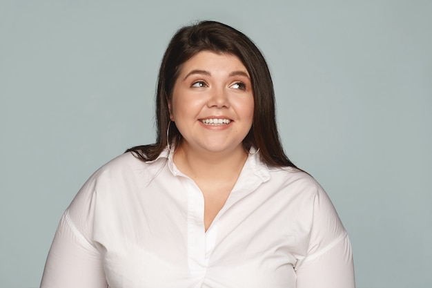 Joy, happiness and positive human emotions. Beautiful attractive young woman employee with curvy body dressed in extra large white shirt smiling broadly, being happy excited with good news