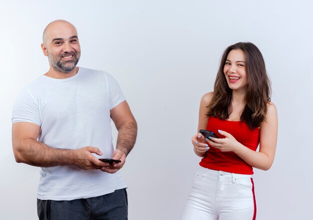 Радостная взрослая пара держит мобильные телефоны и смотрит