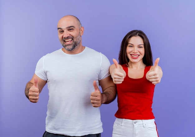 Free photo joyful adult couple looking and showing thumbs up