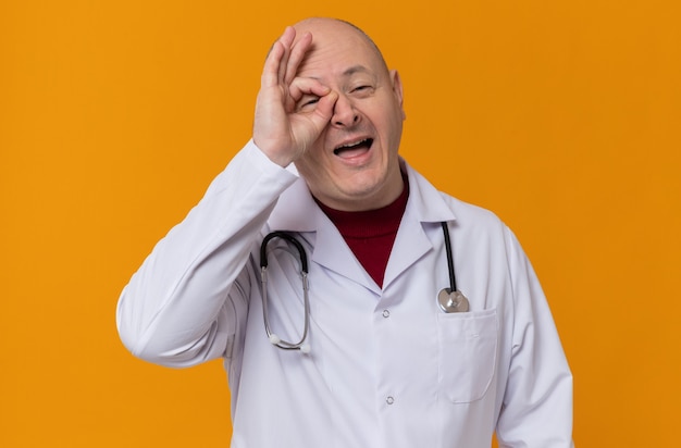 Joyful adult slavic man in doctor uniform with stethoscope through his fingers 