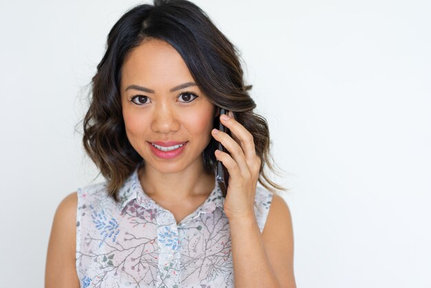 Joyful Asian girl speaking on phone