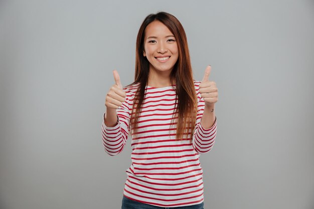 Радостная азиатская женщина показывает палец вверх двумя руками