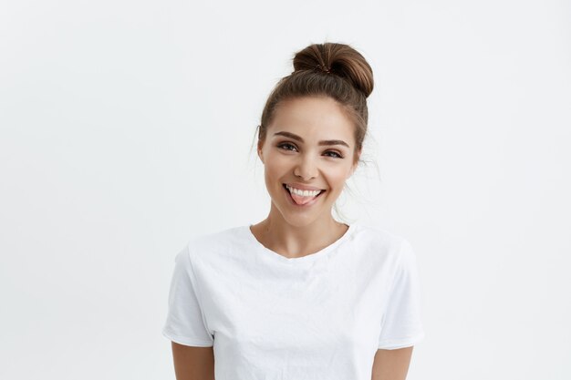 Joyful attractive european woman with stylish hairstyle showing tongue and smiling, being in good mood