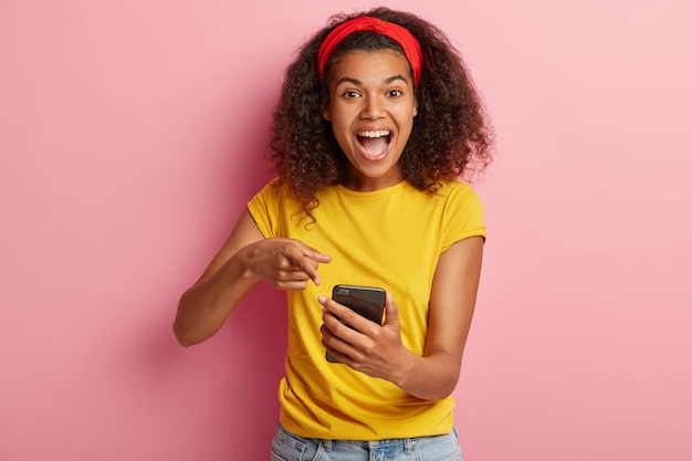 Joyful beautiful teenage girl with curly hair posing in yellow tshirt