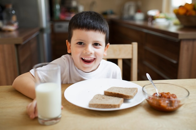 Joyful boy playing around while eating 