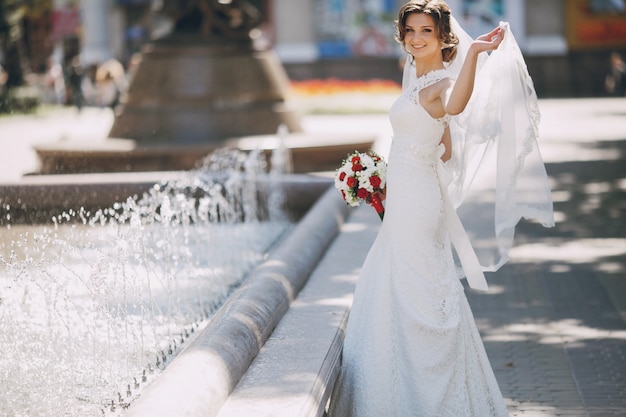 Joyful bride holding the veil with her left hand