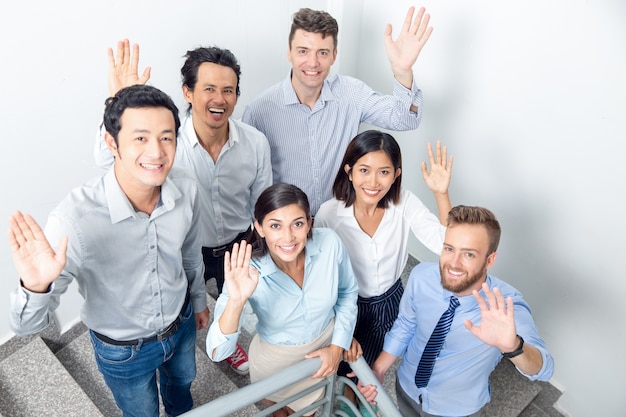 Free photo joyful business team waving on office stairway
