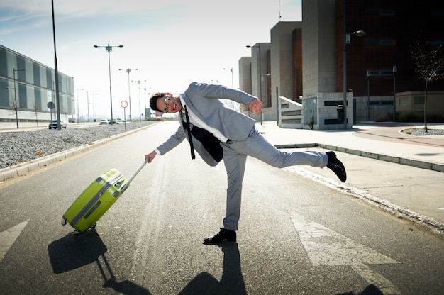 Free photo joyful businessman playing with his suitcase