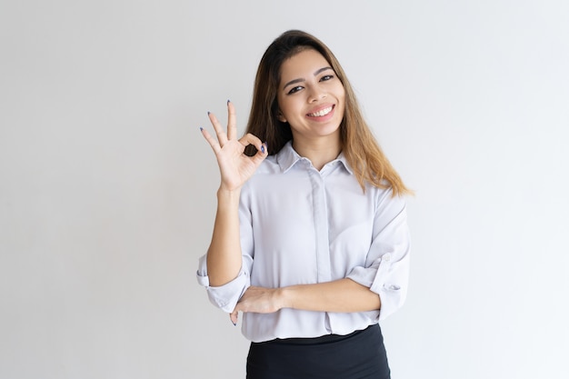 Joyful businesswoman gesturing OK