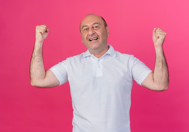 Joyful casual mature businessman doing yes gesture isolated on pink background