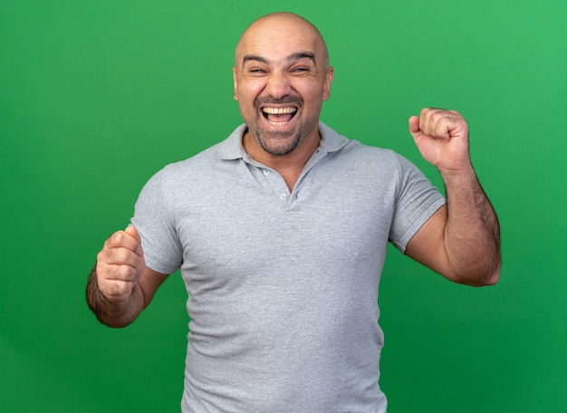 Joyful casual middle-aged man doing yes gesture isolated on green wall