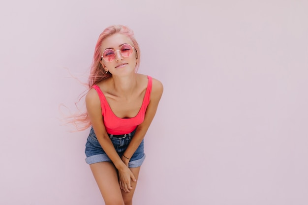 Joyful caucasian woman with pink hair posing with cute smile.