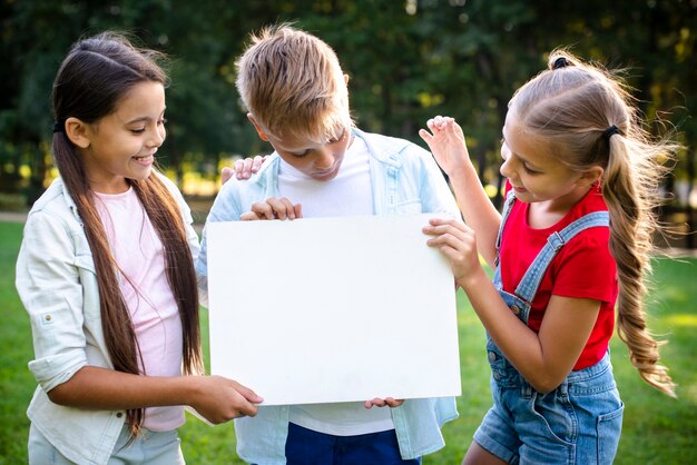 Joyful children holding a blank paper