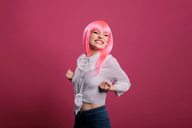 Joyful confident woman celebrating big win and success, posing in front of camera over pink background. Feeling happy and excited about achievement and wonderful triumph, winner style.