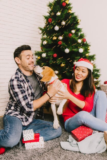 Joyful couple celebrating christmas with dog