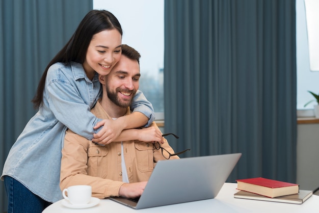 Foto gratuita coppie allegre allo scrittorio con il computer portatile