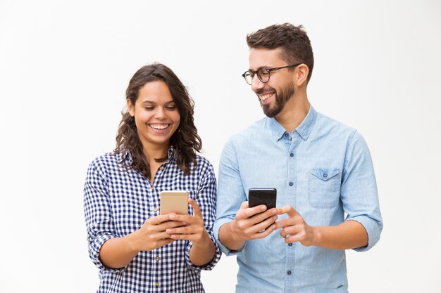 Joyful couple using smartphones