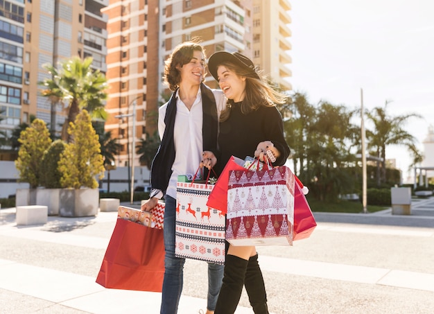 Joyful couple walking with Christmas shopping bags