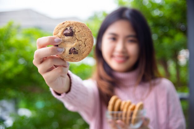 Joyful cute teenage holding cookie at home