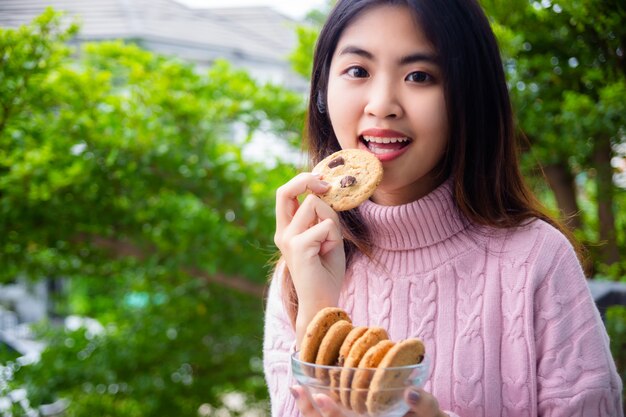 Joyful cute teenage holding cookie at home