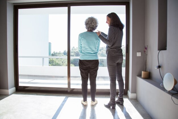 Joyful daughter showing to mother her new apartment