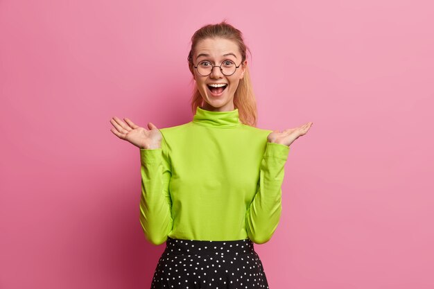 Joyful European girl raises hand reacts on good news