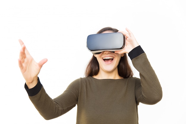 Joyful excited woman in VR headset laughing and touching air