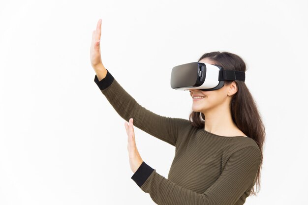 Joyful excited woman in VR headset touching air