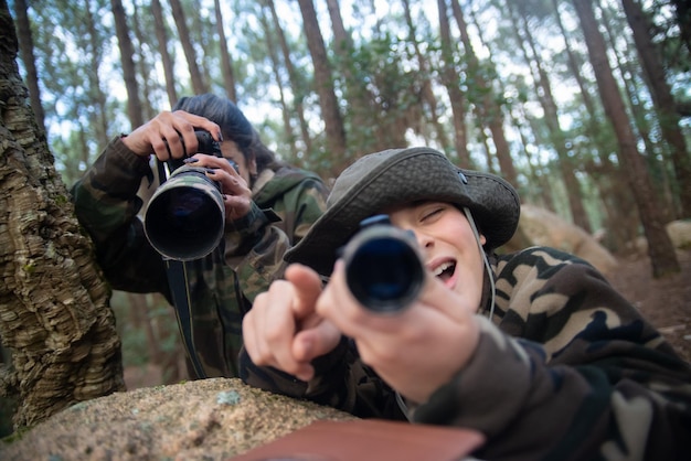 Joyful family taking pictures in forest. Mother and son directing lens at camera. Parenting, family, leisure concept