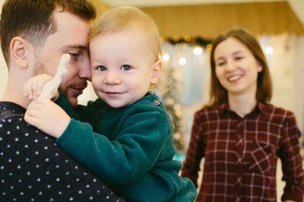 Padre gioioso tiene il suo figlio abbastanza piccolo in maglione verde