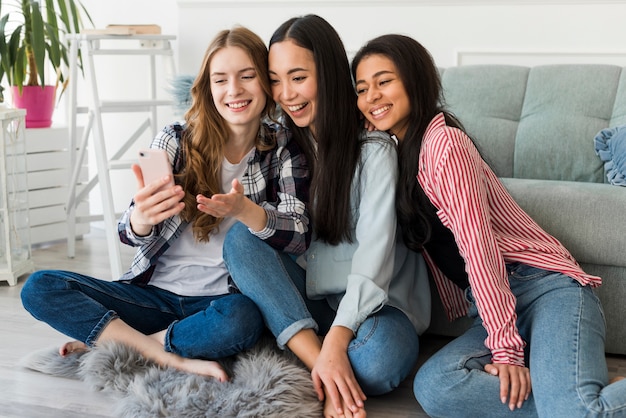 Joyful friends taking selfie on smartphone