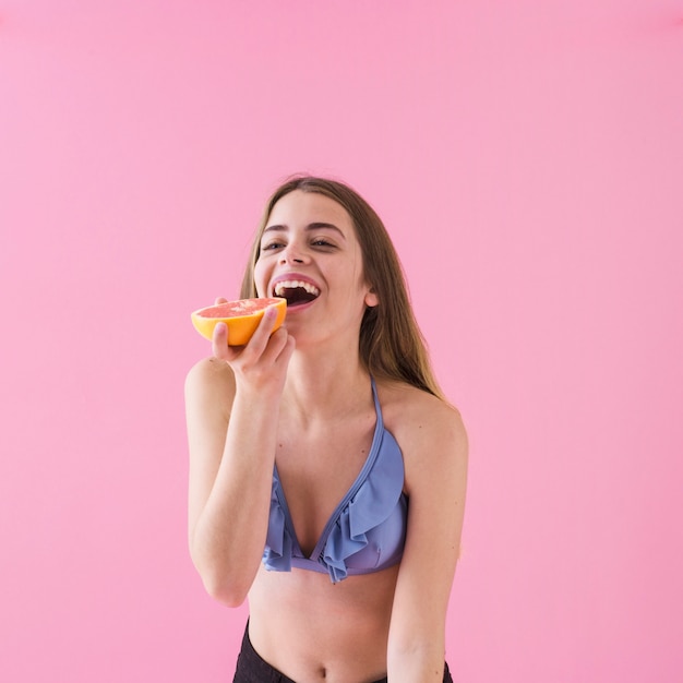 Joyful girl in bikini with grapefruit