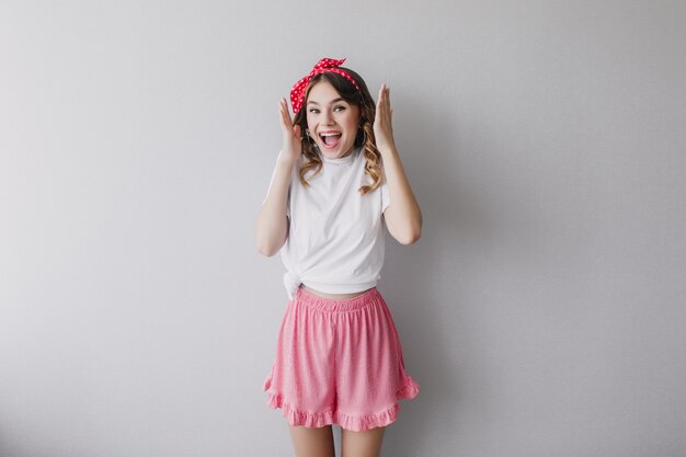 Joyful girl in cute pink shorts funny posing. Indoor photo of caucasian inspired lady with curly hair.