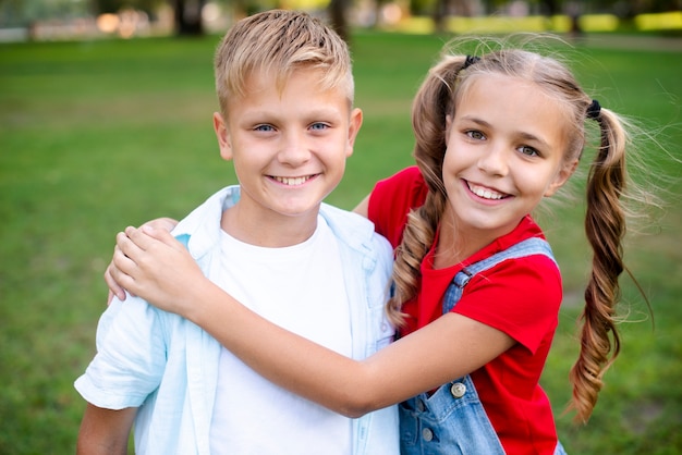 Foto gratuita ragazzo d'abbraccio della ragazza allegra in parco