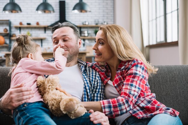 Joyful girl touching her father nose in home