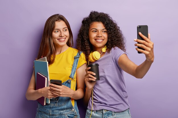 Joyful girlfriends posing with their phones