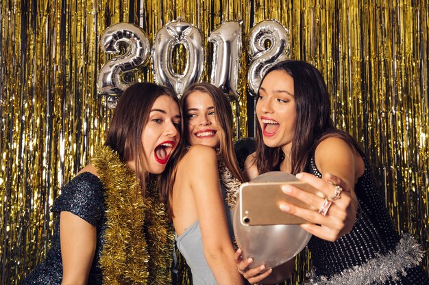 Joyful girls taking selfie on new year party