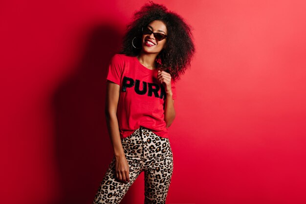 Joyful gorgeous woman in t-shirt smiling on red wall