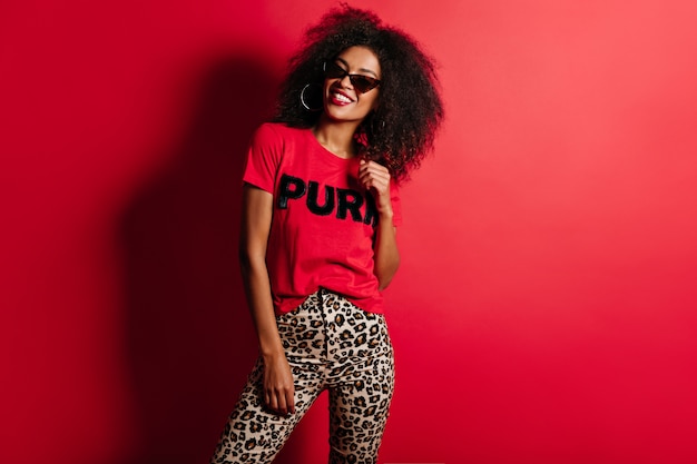 Joyful gorgeous woman in t-shirt smiling on red wall