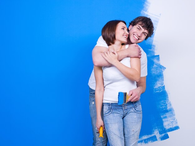 페인트 벽 근처에 서 즐거운 행복 포용 사랑의 부부