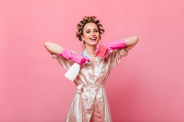 Joyful housewife in silk robe holding sponge for washing dishes