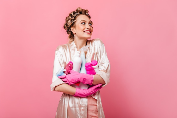 Free Photo joyful housewife woman in pink robe holding detergent