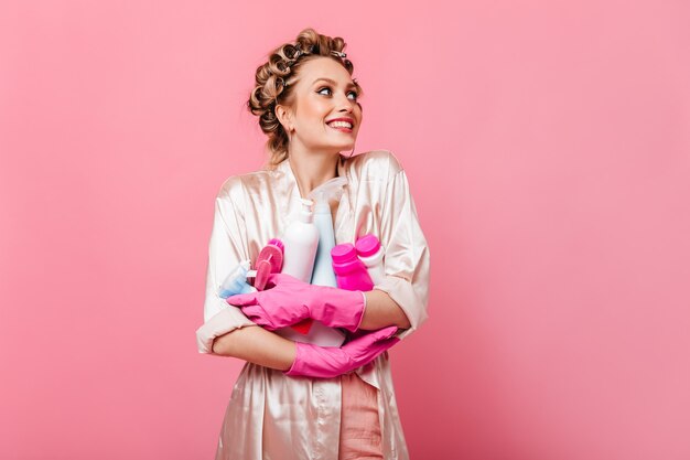 Радостная домохозяйка в розовом халате с моющим средством